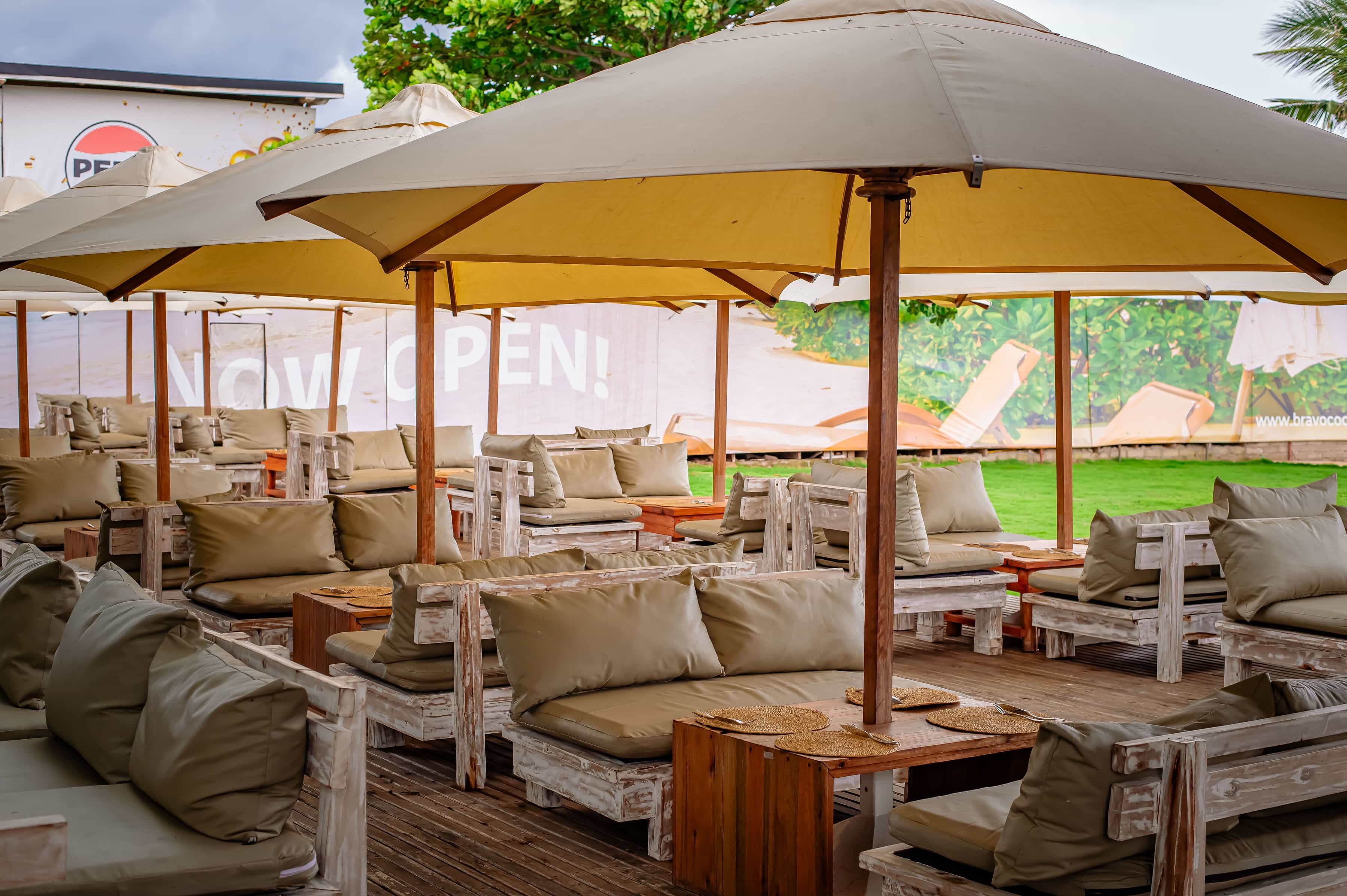 Covered outdoor lounge seating with cushioned sofas and large umbrellas at Bravo Coco Beach.
